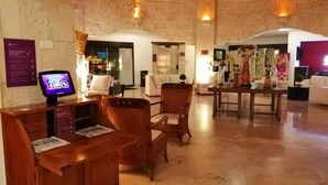 Eine Lobby mit Empfangstresen, Sitzgelegenheiten und einer Treppe zu einer oberen Ebene.