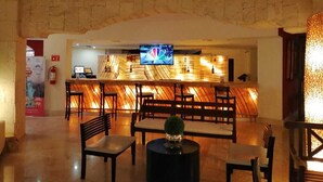 Eine Lobby mit einer Steinwand, einem Barbereich inklusive Fernseher sowie Sitzgelegenheiten.