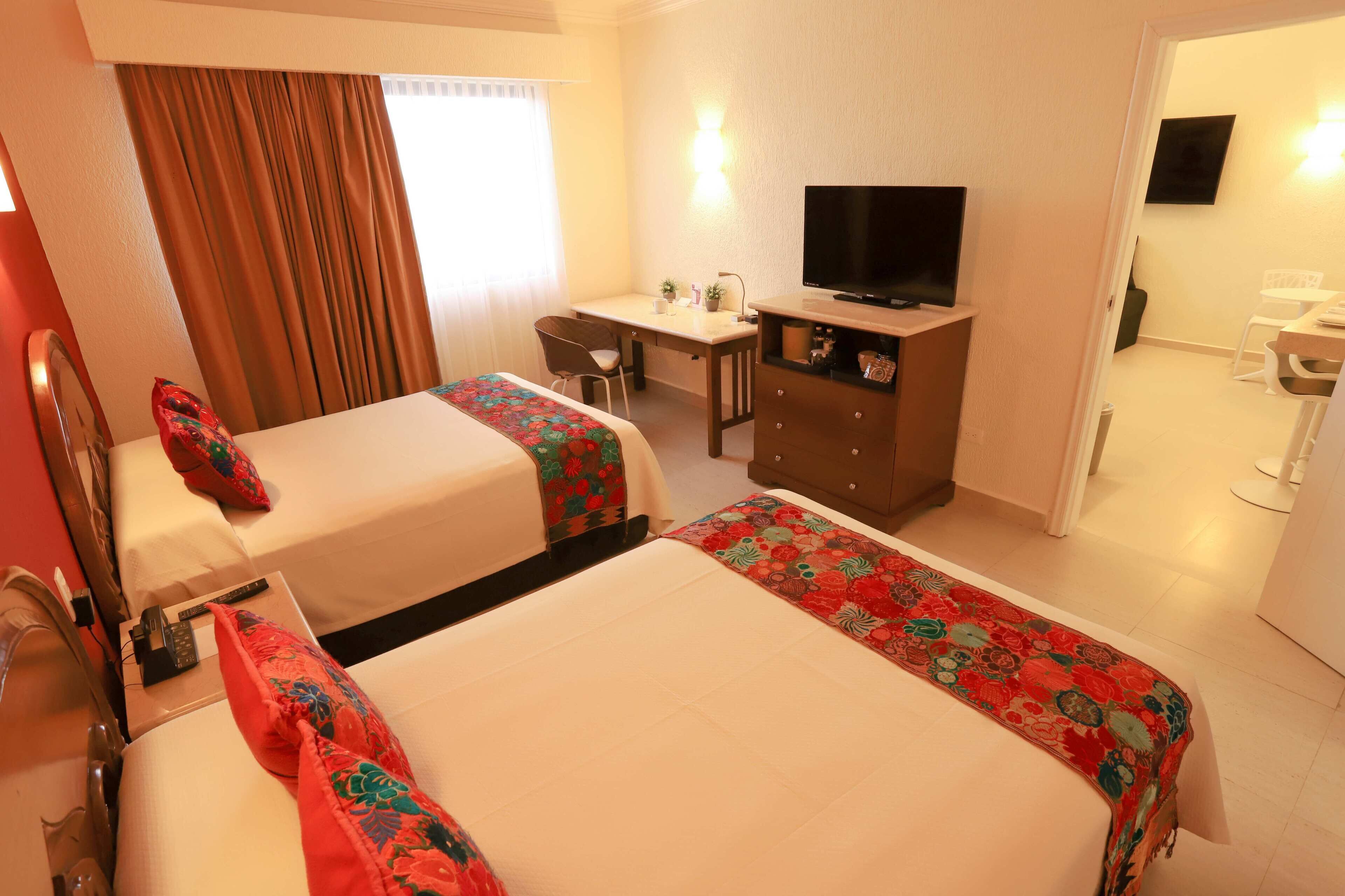 Une chambre d’hôtel avec deux lits, un bureau, une télévision et une salle de bain.