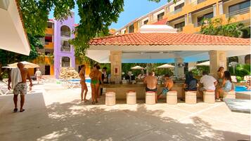A poolside area with lounge chairs, a bar, and a covered seating area.