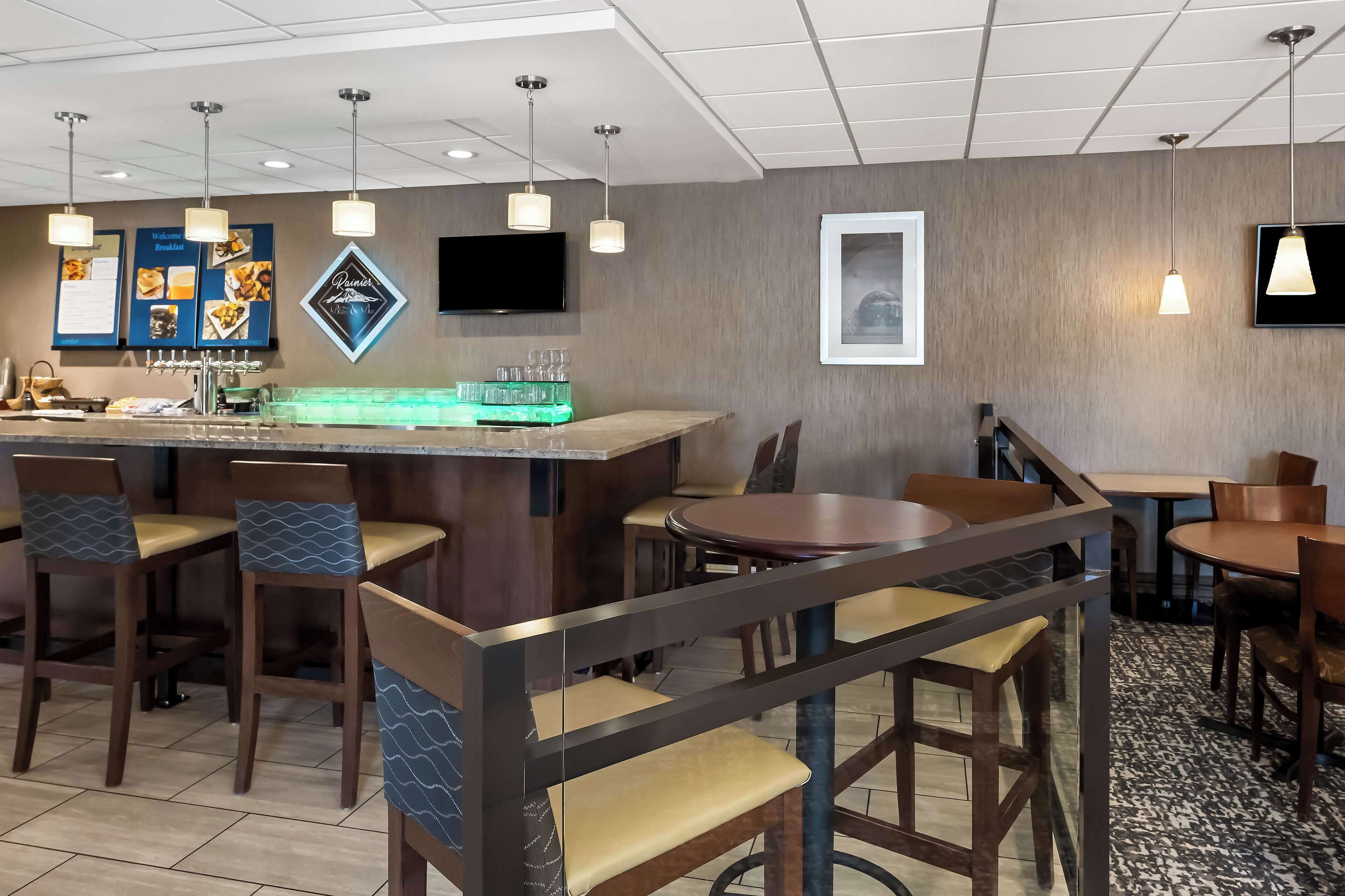 A hotel lobby with a bar area, seating arrangements, and a television mounted on the wall.