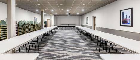 A conference room with long tables, chairs, and a patterned carpet.