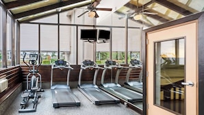 A gym with treadmills, elliptical machines, and a ceiling fan.
