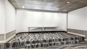 Uma sala de conferências com carpete estampado, uma mesa branca e um teto com iluminação embutida.