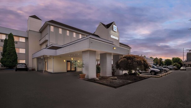 A hotel with a modern design, featuring a covered entrance and multiple windows.