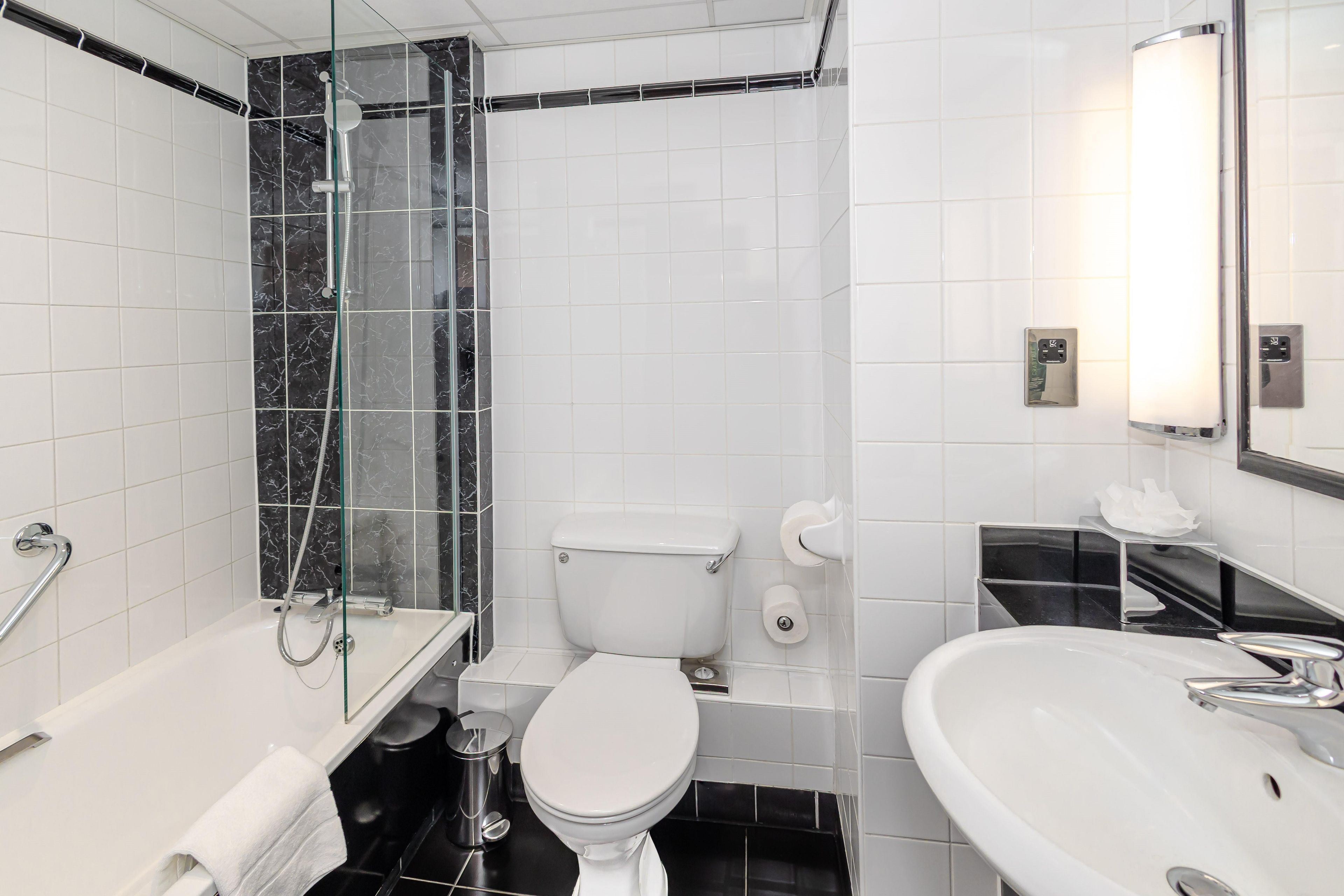 A modern bathroom with a glass-enclosed shower, a white toilet, and a sink with a mirror.