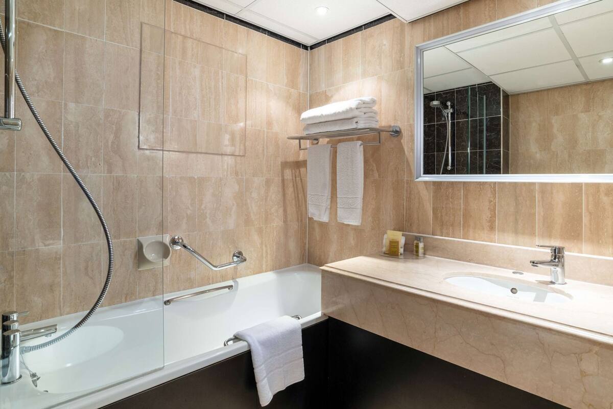 A modern bathroom with a bathtub, a shower, a sink, and a mirror.