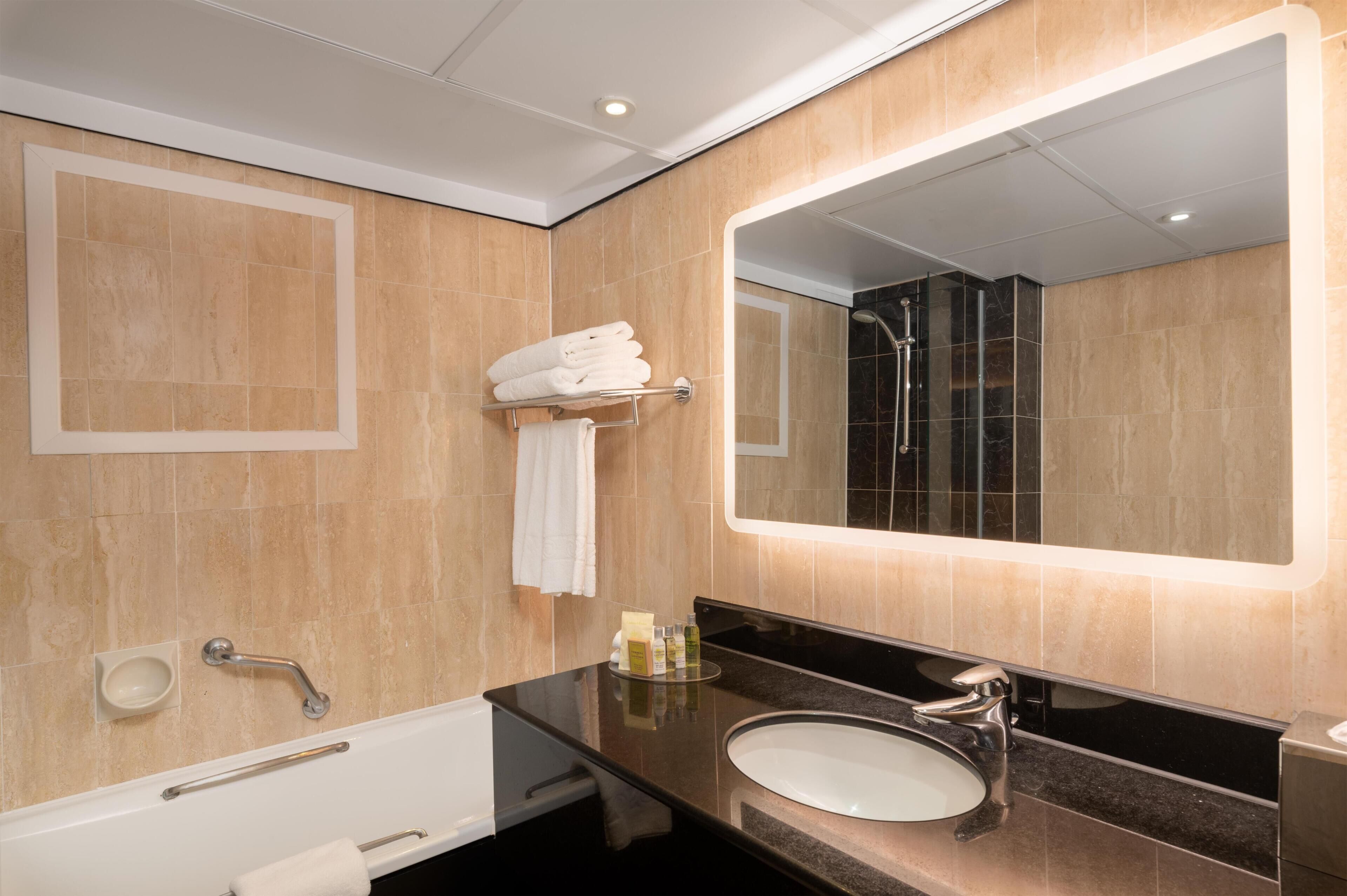 A modern bathroom with a bathtub, a sink, a mirror, and a shower.
