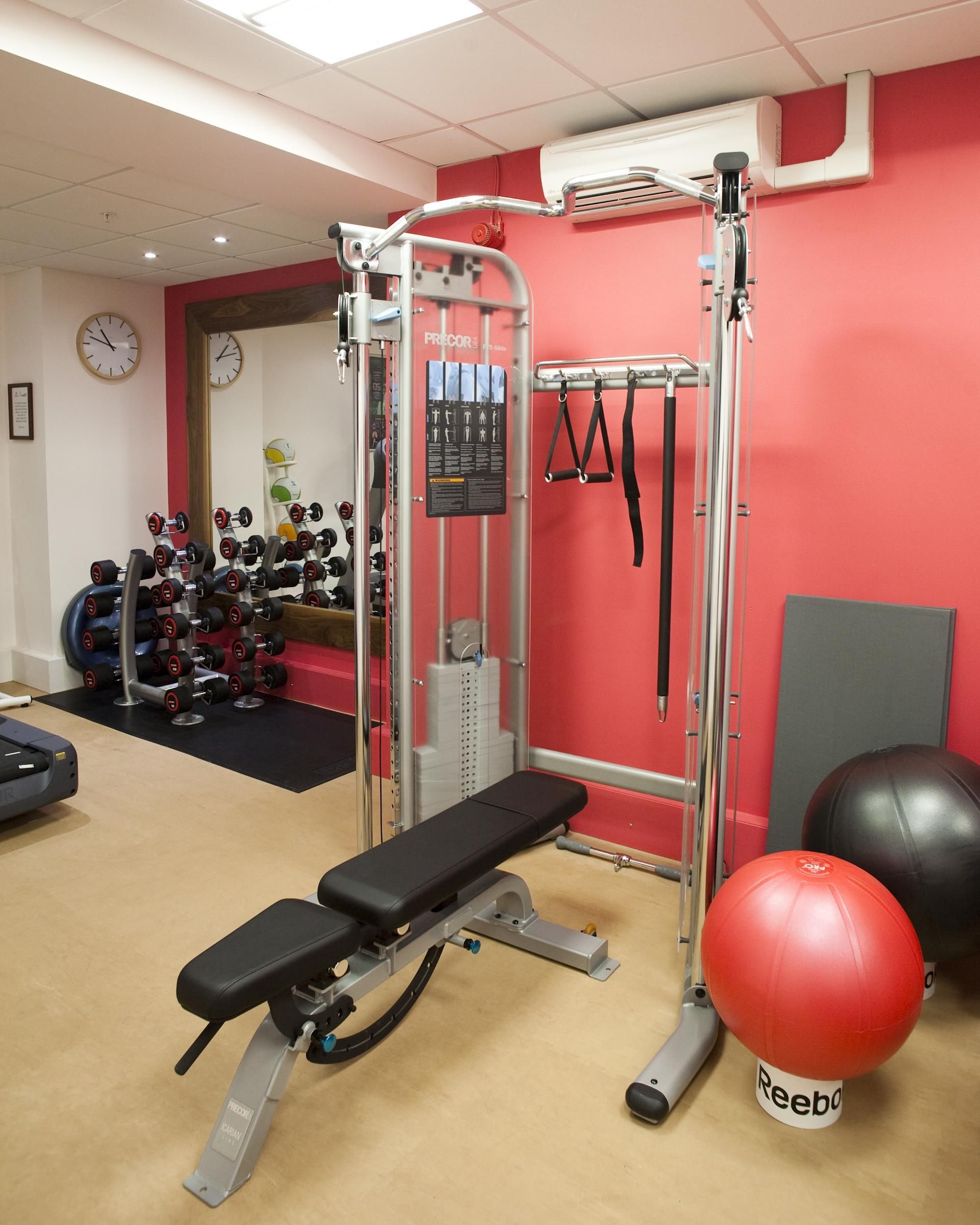 Una palestra con panche, rastrelliere per pesi, una panca per squat e palle da ginnastica.