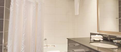 Un baño moderno con bañera, inodoro, lavamanos y un espejo grande.