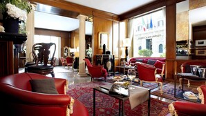 Un hall espacioso con sofás de cuero rojo, una mesa de centro y un amplio ventanal con vistas a la ciudad.