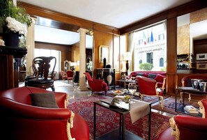 A spacious lobby with red leather sofas, a coffee table, and a large window with a view of the city.