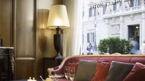 Un lobby de hotel lujoso con un sofá rojo, una mesa con copas de vino y una lámpara.