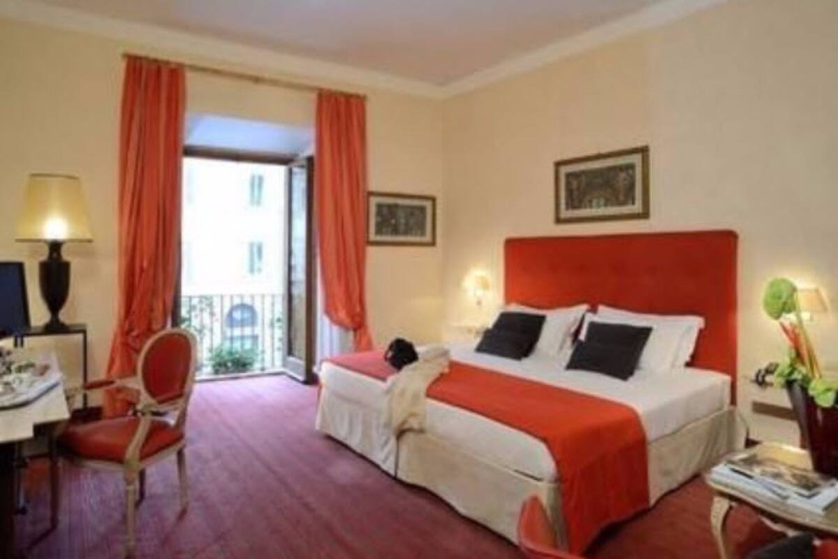 A hotel room with a bed, a desk, a chair, and a window with curtains.