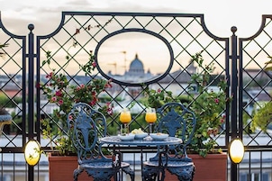 A table with chairs and drinks, a mirror, and a view of a building through a metal fence.