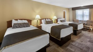 Une chambre d’hôtel avec trois lits, un bureau et une chaise.