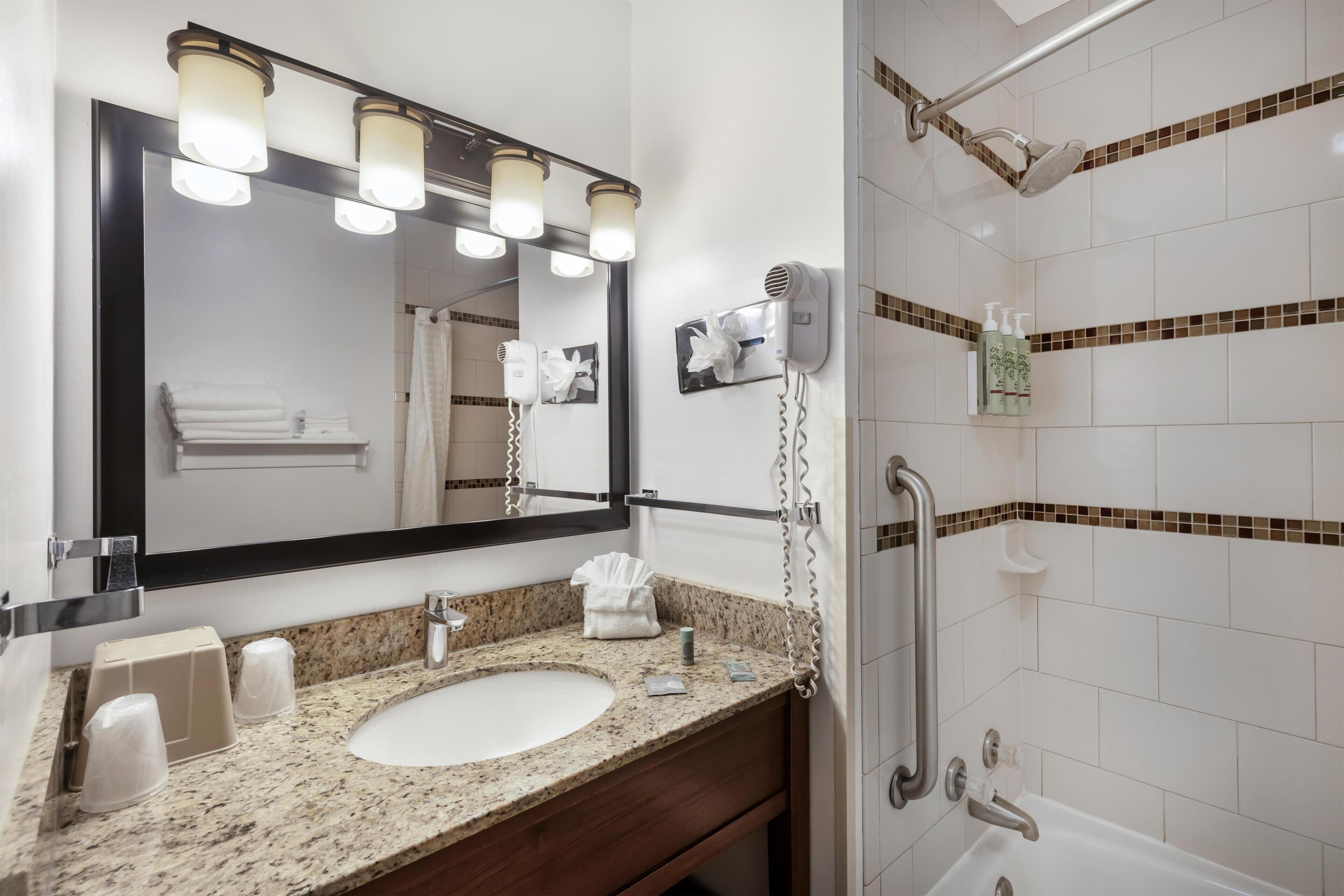 Une salle de bain équipée d’un lavabo, d’un miroir, d’un porte-serviettes et d’un espace douche.