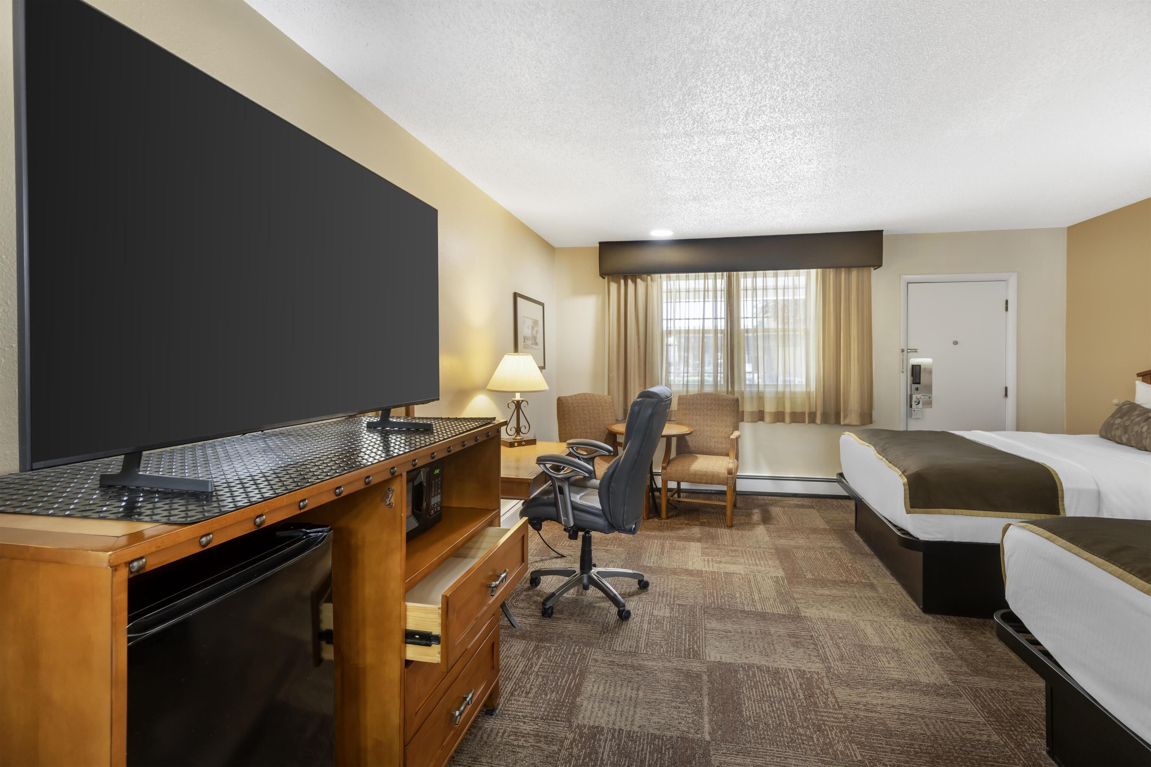 Een hotelkamer met een bureau, stoel, bed en een televisie.