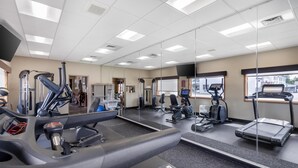 Une salle de sport équipée de matériel d’exercice, dotée d’un mur avec des miroirs et d’une fenêtre offrant une vue agréable.