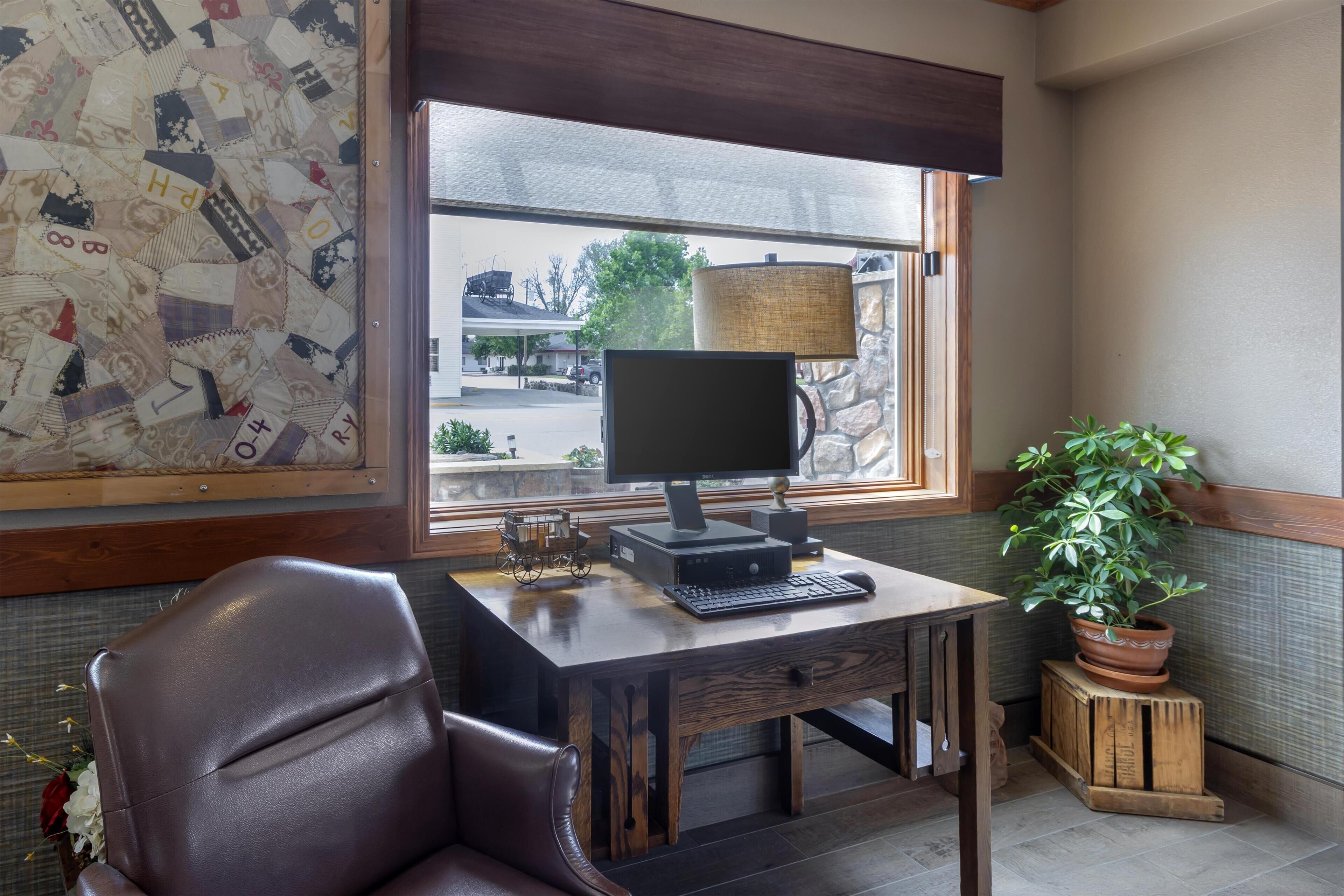 A room with a desk, chair, window, lamp, and a potted plant.