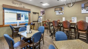 L’intérieur d’un restaurant, avec ses tables et ses chaises, une fenêtre donnant sur un paysage agréable et des éléments décoratifs sur les murs.