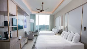 Habitación de hotel con una cama grande, un escritorio, una silla, un televisor y una ventana con vista a la ciudad.