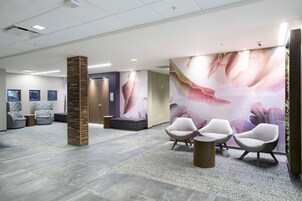 Un área de espera moderna con mostrador de recepción, asientos y un gran mural floral en la pared.