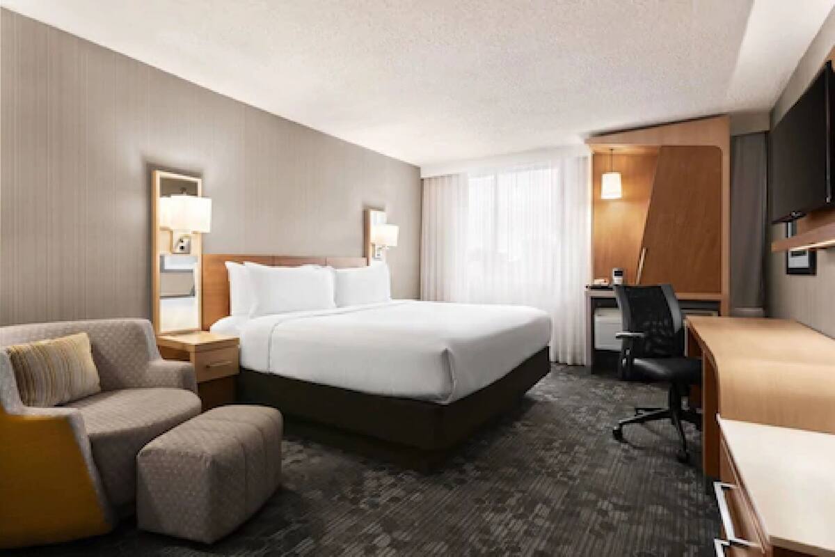 A hotel room with a large bed, a desk, a chair, and a sofa.