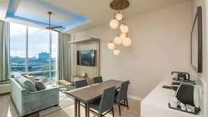 Una habitación de hotel moderna con comedor, sofá, televisor y cafetera.