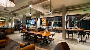 Un amplio espacio interior con una larga mesa de madera y sillas, una zona de bar y un área de estar con sofás.