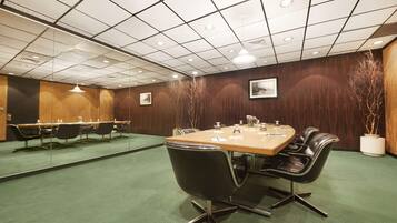 A conference room with a long table, black chairs, and a green carpet.