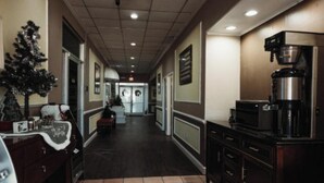 Corredor de hotel com máquina de café, árvore de Natal e balcão de recepção.