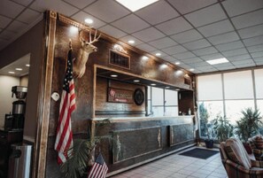 A reception area with a wooden reception desk, an American flag, and a mounted deer head.