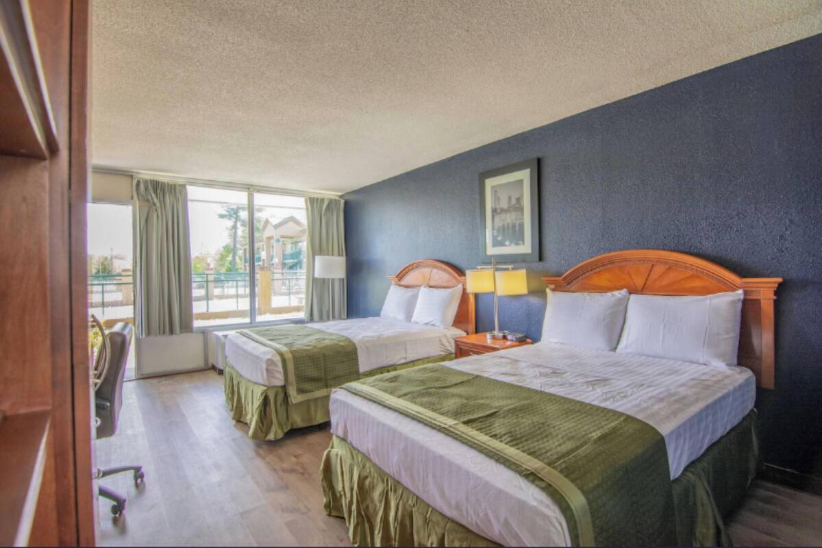 A hotel room with two beds, a desk, and a chair.