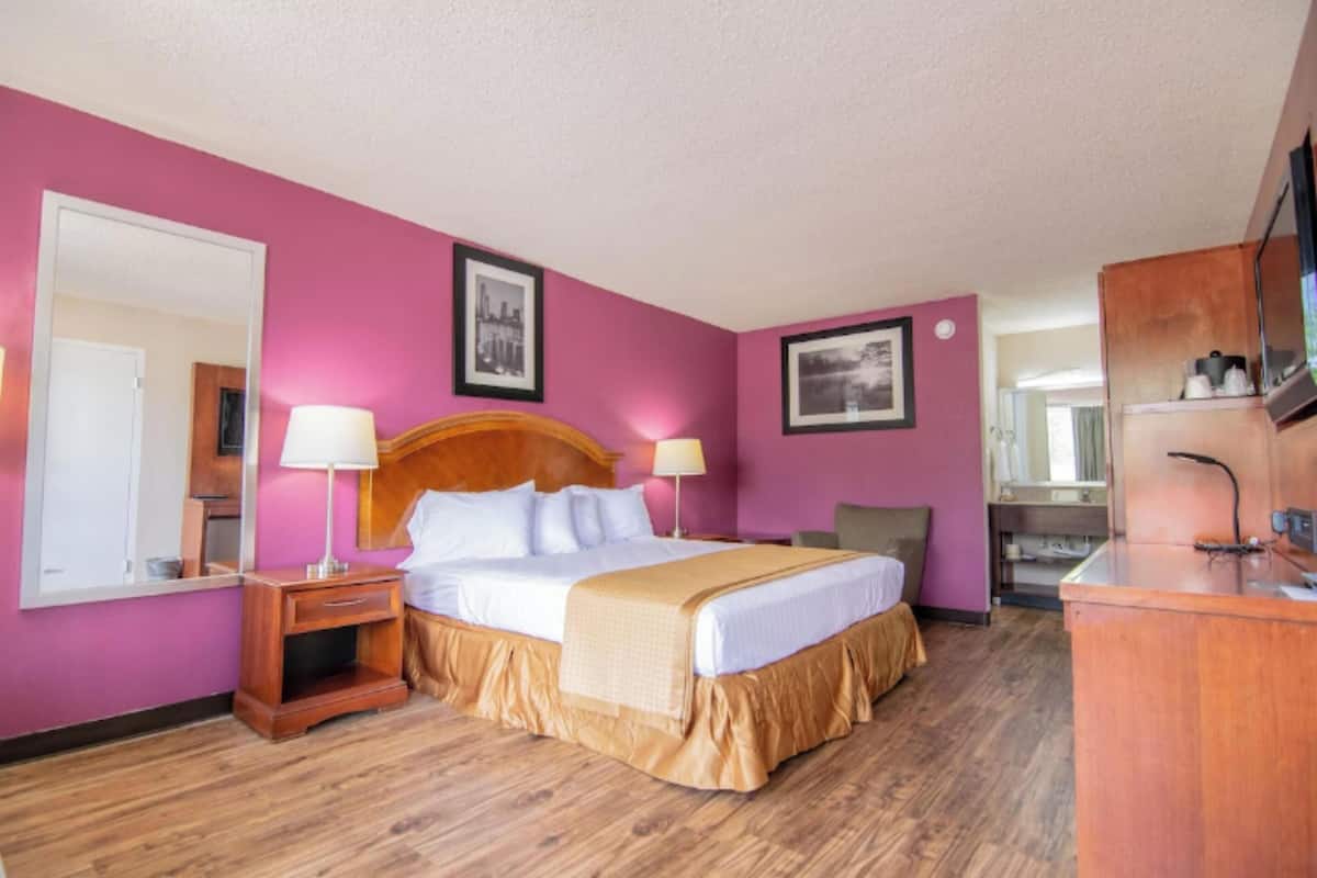 A hotel room with a bed, bedside tables, a desk, and a mirror.