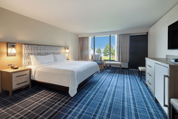 Une chambre d’hôtel avec un grand lit, un bureau, une chaise et un téléviseur.