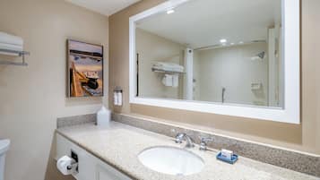 A bathroom with a large mirror, a sink, and a toilet. There is a painting on the wall and a towel rack above the sink.