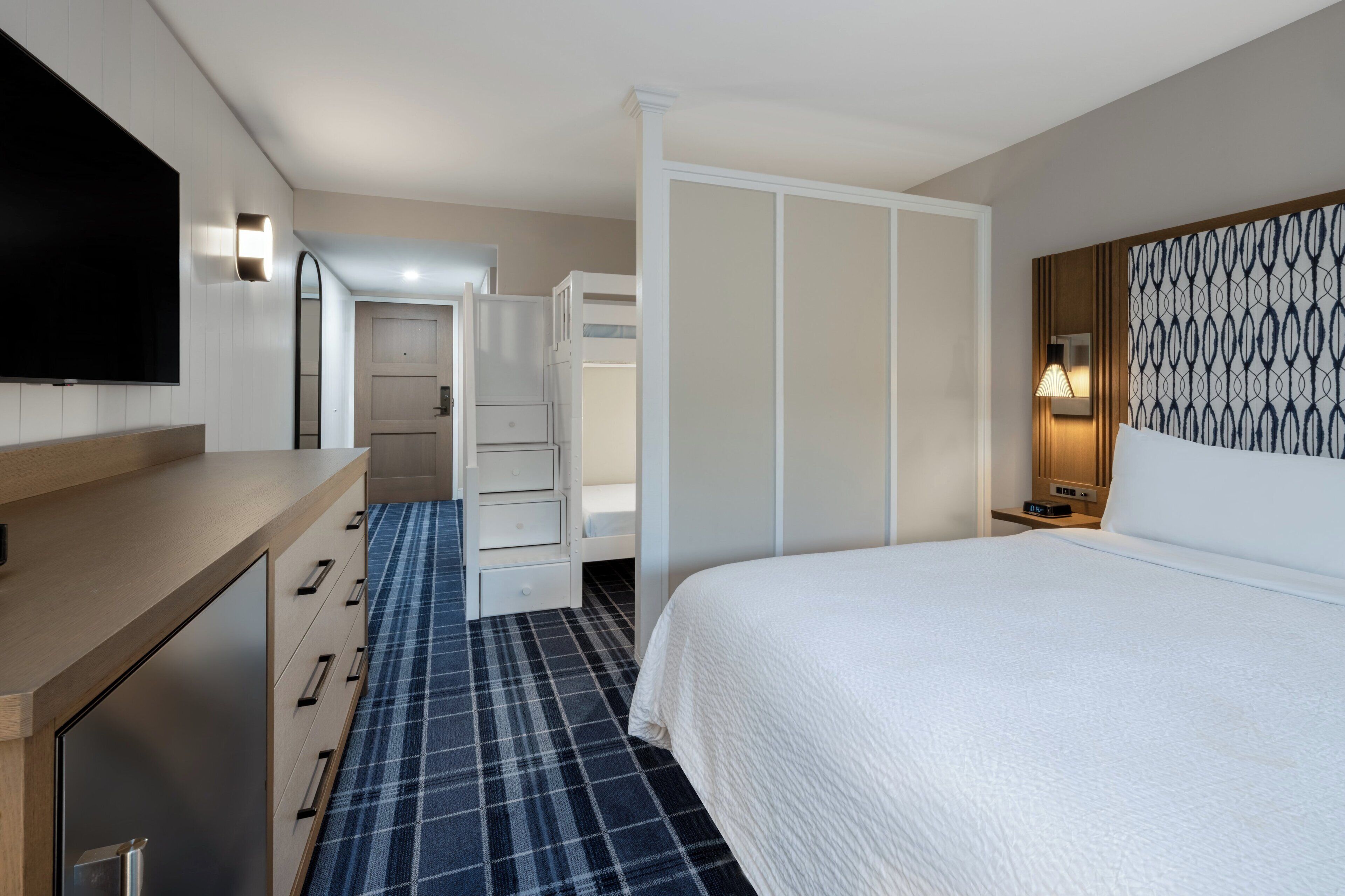 Een hotelkamer met een bed, een televisie, een bureau, een kledingkast en een badkamer.