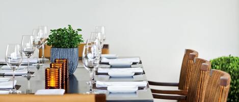 Un comedor con una mesa larga dispuesta para una comida, rodeado de sillas de madera.