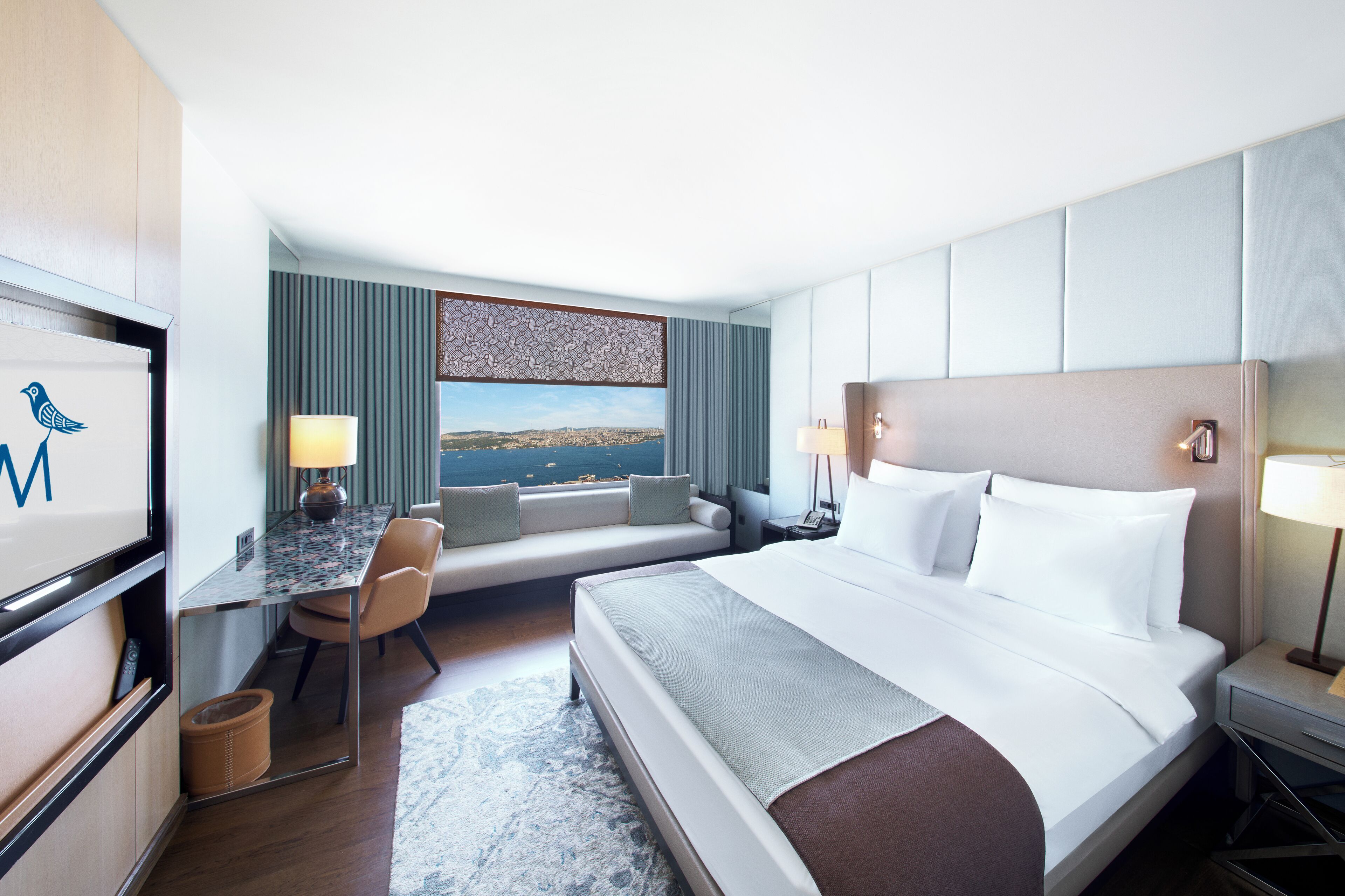 Una camera d'albergo con un letto, una scrivania, una sedia, una televisione e vista mare.