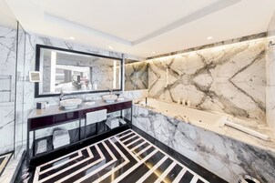 Un baño moderno con un espejo grande, dos lavamanos, una bañera y piso de mármol.