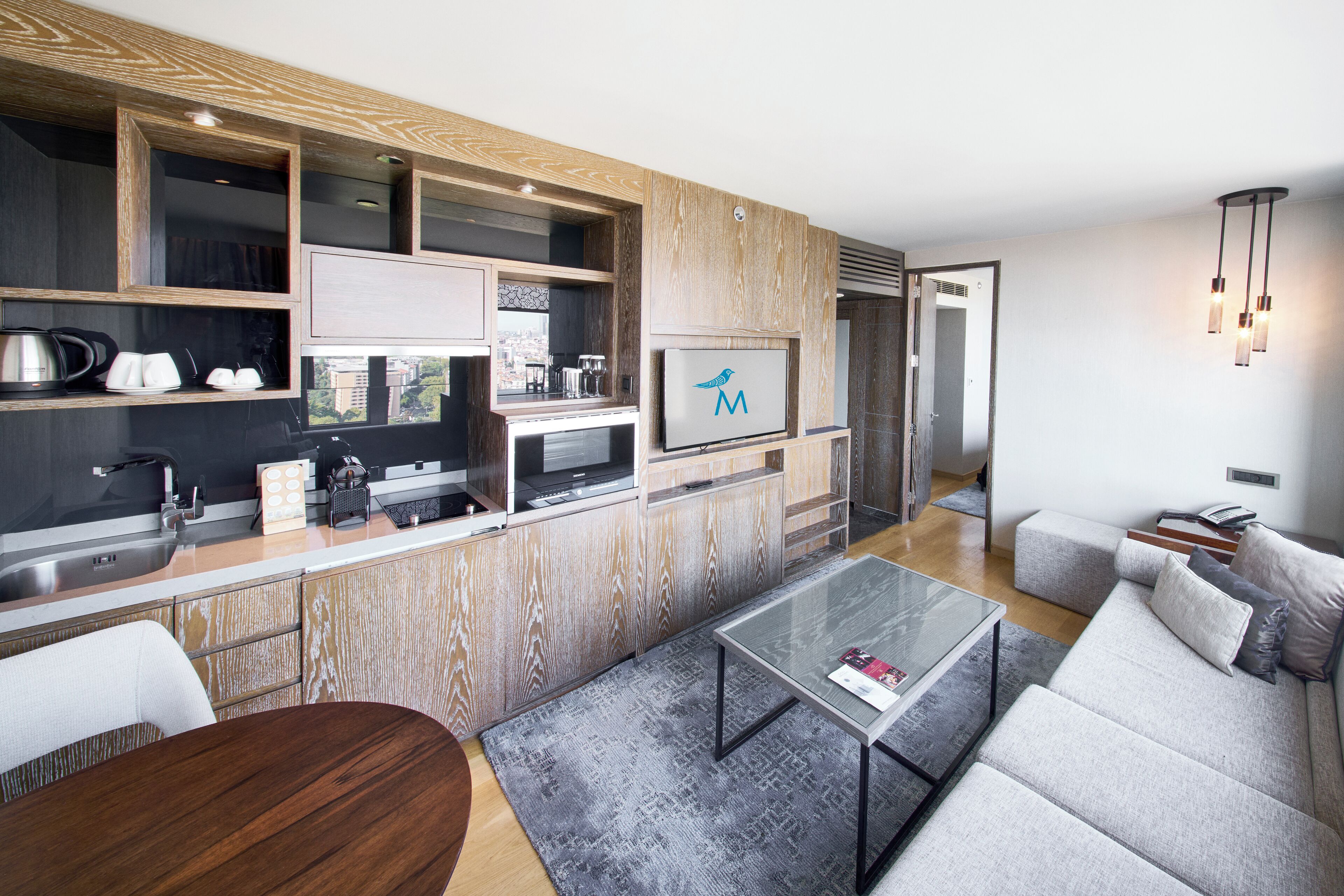 A modern kitchen with wooden cabinetry, a built-in microwave, and a large window overlooking the city.