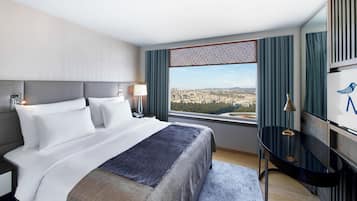 Una habitación de hotel con una cama grande, un escritorio y vistas a la ciudad.