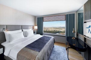 Una habitación de hotel con una cama grande, un escritorio y vistas a la ciudad.