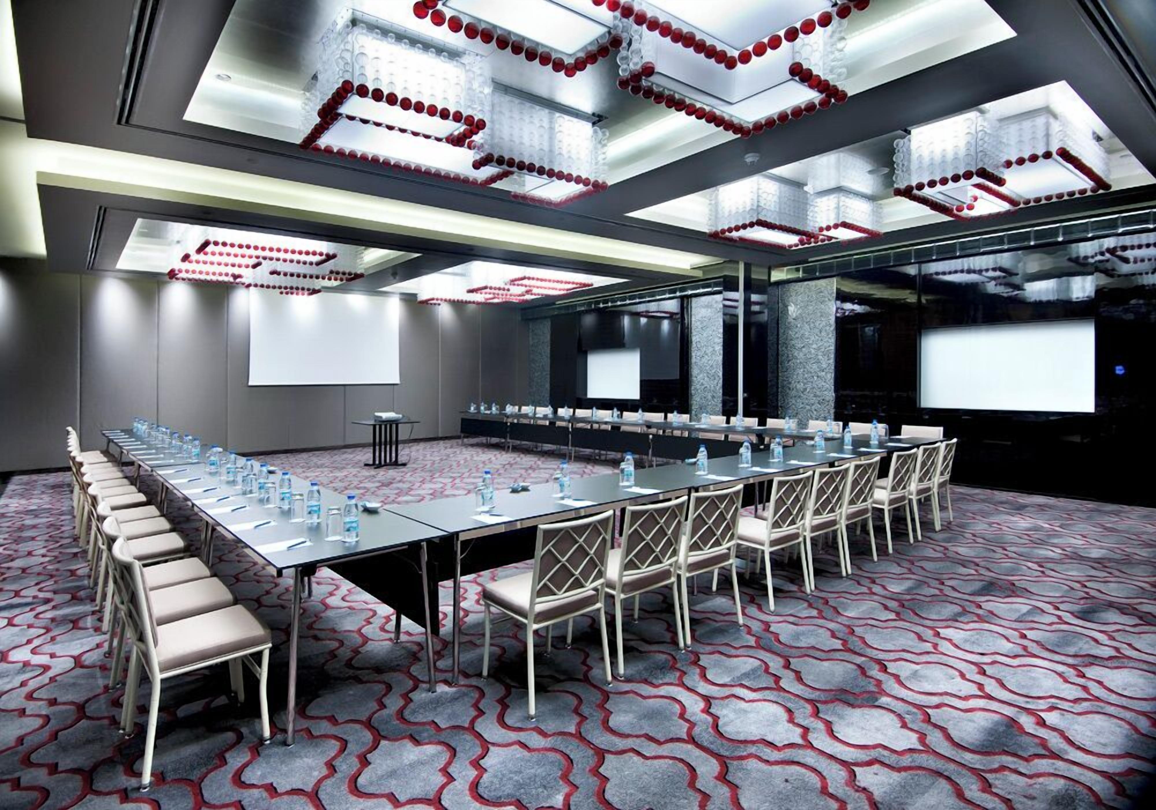 A conference room with a long table, chairs, and a projector screen.