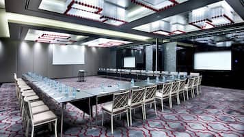 A conference room with a long table, chairs, and a projector screen.