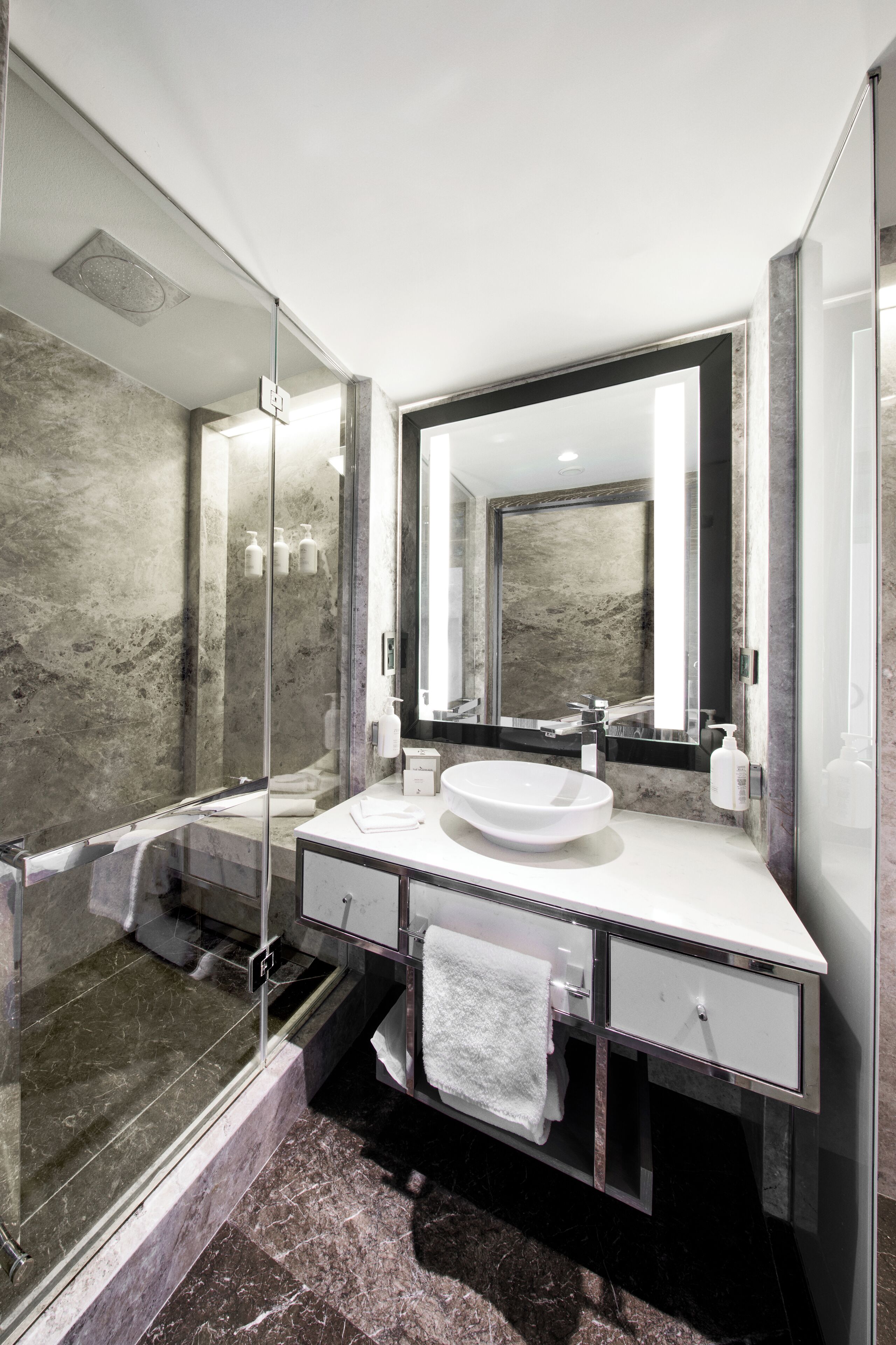 Une salle de bain moderne avec une douche à parois de verre, un lavabo blanc et un grand miroir.