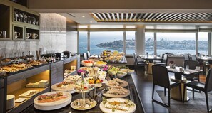 A buffet with various food items and a view of the city from the dining area. - The Marmara Taksim (Istanbul)