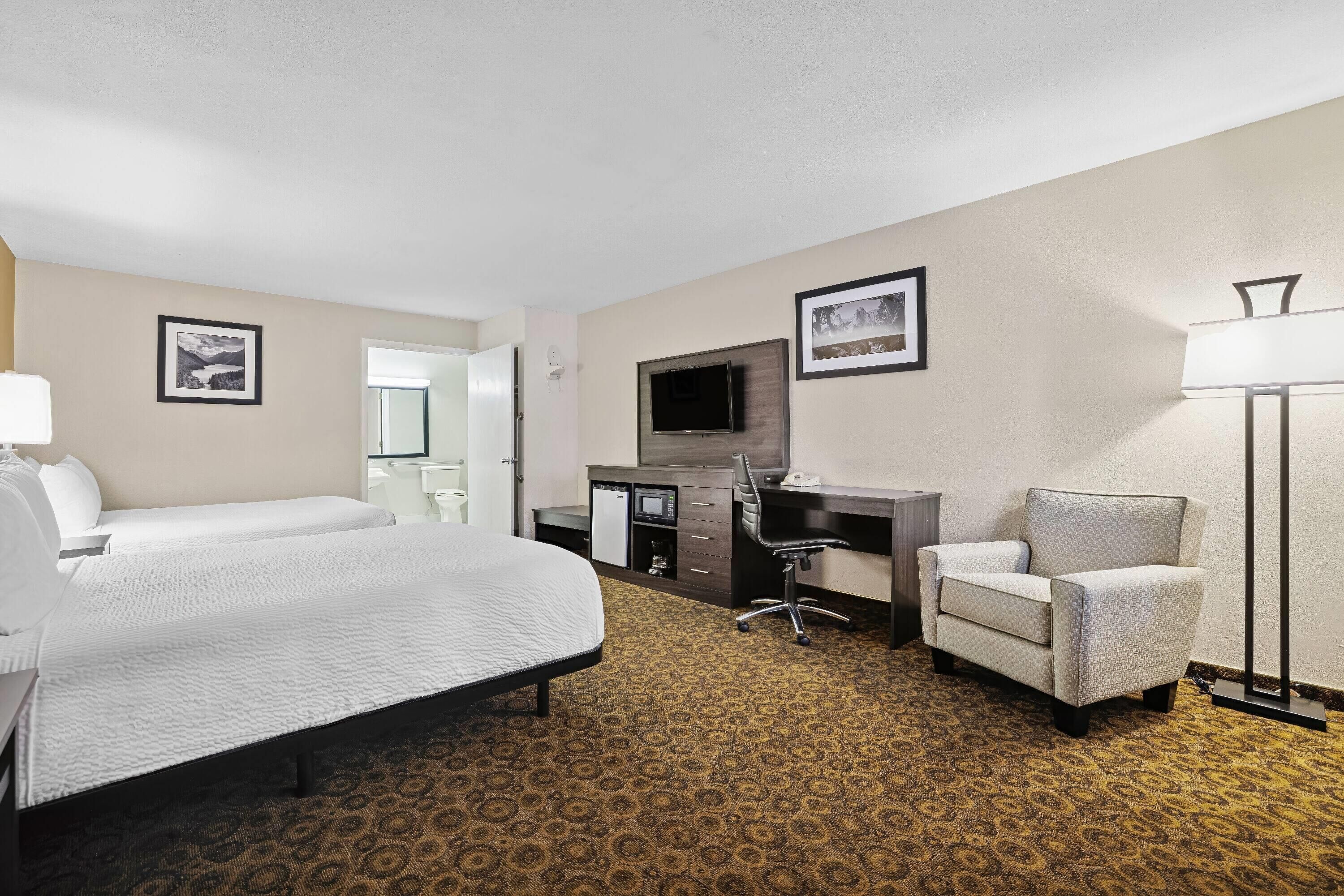 Une chambre d’hôtel avec un grand lit, un bureau avec une chaise, une télévision et une lampe.