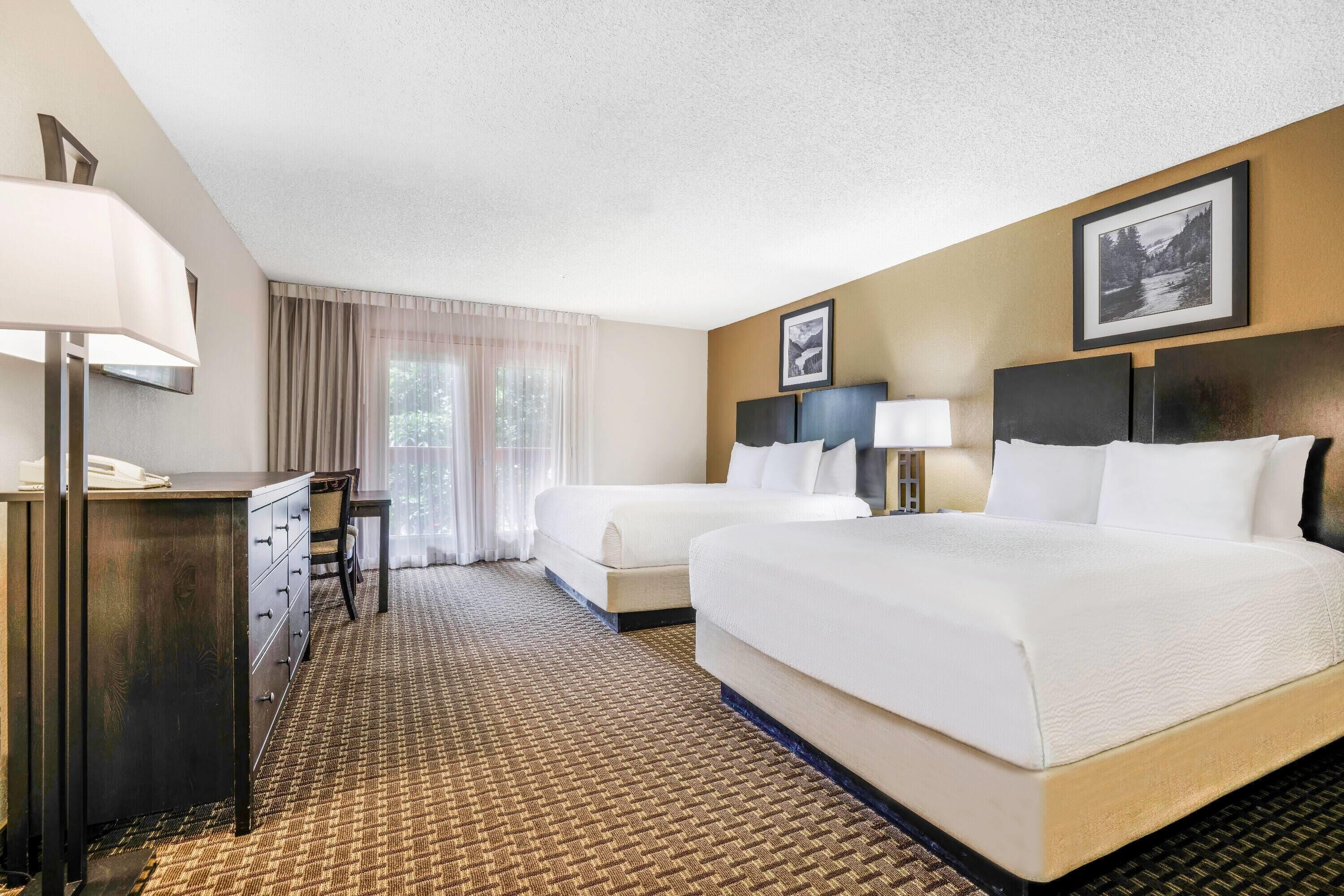 Ein Hotelzimmer mit zwei Betten, einem Schreibtisch und einem Stuhl.